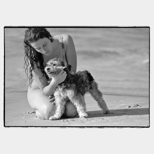Young woman on a beach hugging a dog