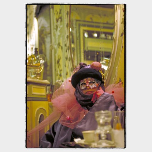 Masked woman sitting at bar table in Venice during Carnival