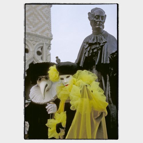 Two masked persons in front of bronze statue of Casanova in Venice