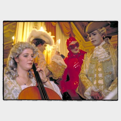 Carnival party in Venice: woman cello player with three masked man listening
