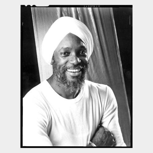 Dark skinned guy with turban and white T-shirt smiling at camera